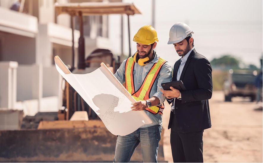 Construction worker and architect review blueprints on an active building site.
